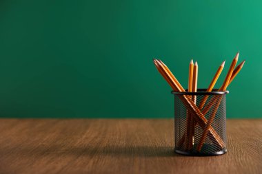 pencils on wooden table with green chalkboard on background