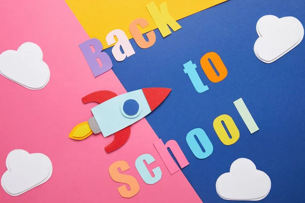 回到学校的字体与云和火箭在彩色纸背景 — 图库照片