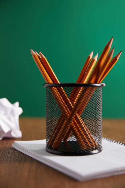 pencils on copybook with green chalkboard on background 