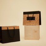 Un sacchetto di shopping su cubo di legno, sacchetto di carta nero su superficie beige