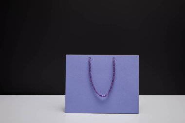 one violet shopping bag on white table isolated on black clipart