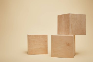 three brown wooden cubes isolated on beige clipart