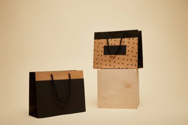 one shopping bag on wooden cube, black paper bag on beige surface clipart