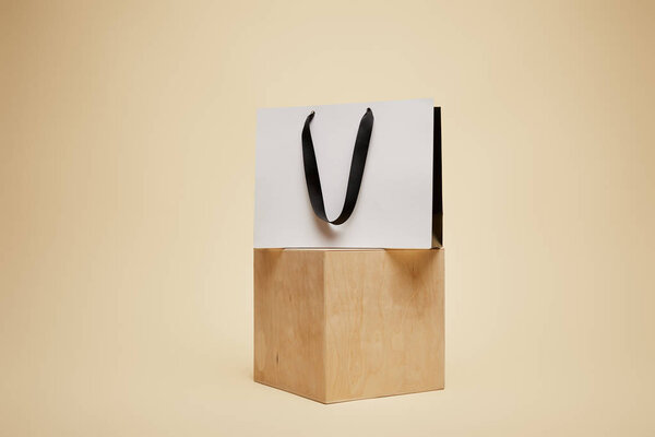 one shopping bag on wooden cube isolated on beige