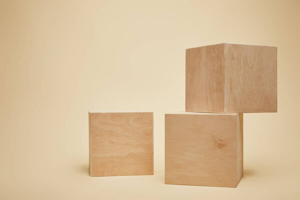 three brown wooden cubes isolated on beige