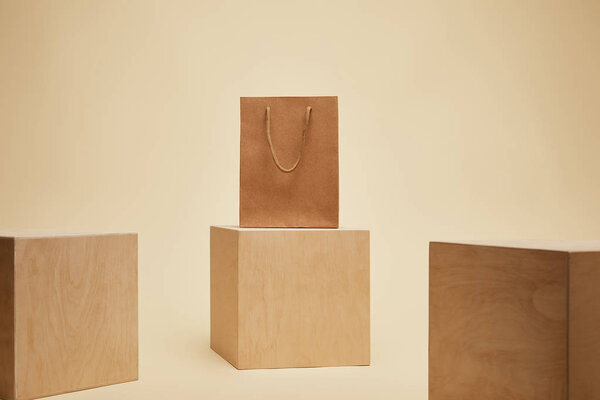 paper shopping bag and three wooden cubes isolated on beige 