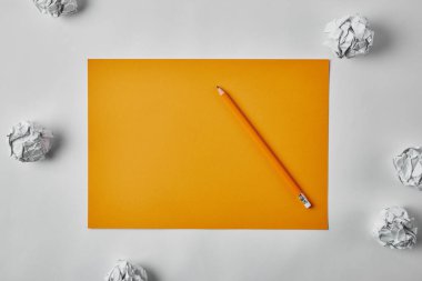 top view of blank yellow paper with pencil surrounded with crumpled papers on white surface clipart