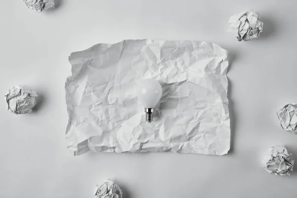 白い表面にしわの白紙の用紙に電球を省電力のトップ ビュー — ストック写真