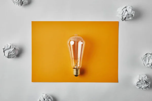 Top View Incandescent Lamp Blank Yellow Paper Surrounded Crumpled Papers — Stock Photo, Image