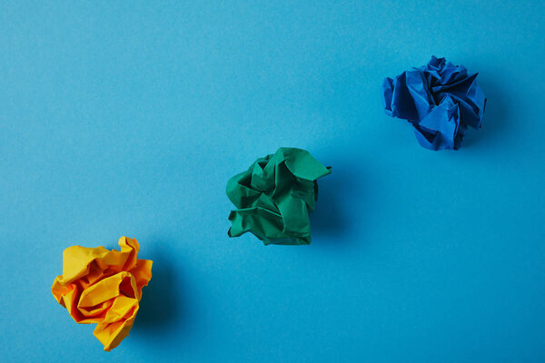 top view of colorful crumpled papers on blue surface