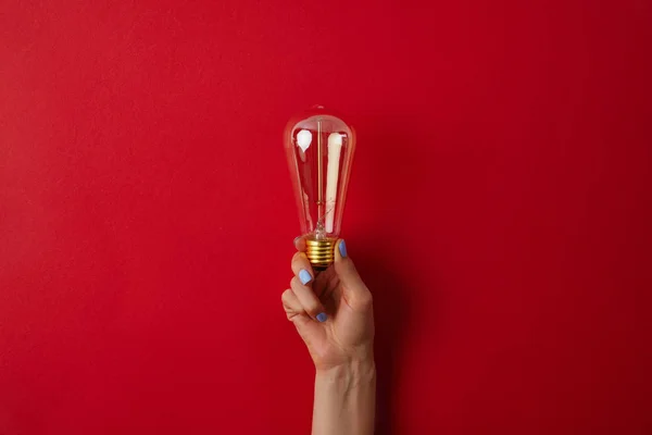 Tiro Recortado Mujer Sosteniendo Lámpara Incandescente Vintage Superficie Roja — Foto de Stock