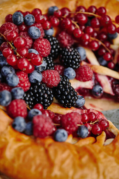 close up of tasty berries pie with raspberries, currants, blueberries and blackberries