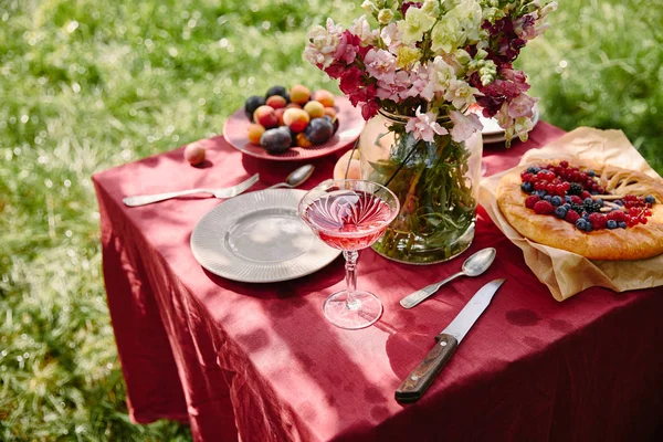 ワイングラス ベリーのパイ 庭のテーブルの上の花の花束 — ストック写真