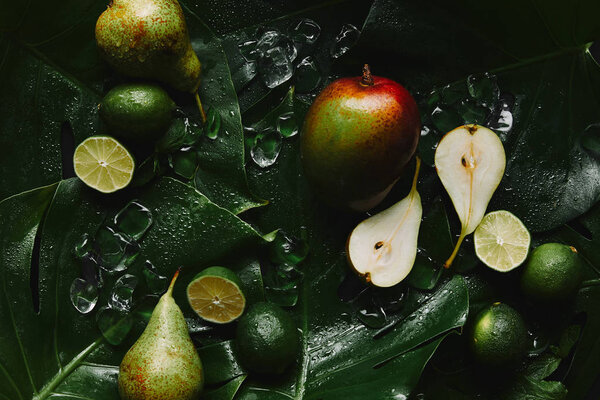 top view of fresh ripe fruits, ice cubes and beautiful green tropical leaves 