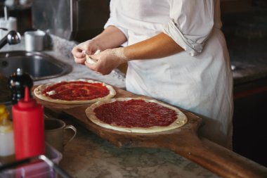 Şef peynir parçaları koyarak pizza lokanta mutfağı kadeh kırpılmış