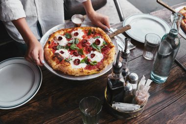 kadın taşıma plaka restoran masada hizmet için pizza margherita ile kadeh kırpılmış