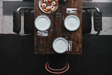 top view of pizza margherita on tray and table setting at restaurant clipart