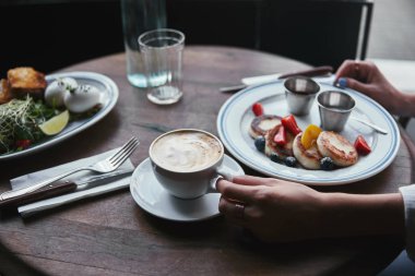 Lor krep, salata ve restoranda ahşap masa kahve kadınla kadeh kırpılmış