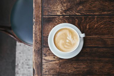 top view of cup of coffee with latte art on rustic wooden table clipart