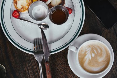 fincan kahve ve rustik ahşap masa üstünde smartphone ile plaka üzerinde lezzetli lor krep üstten görünüm