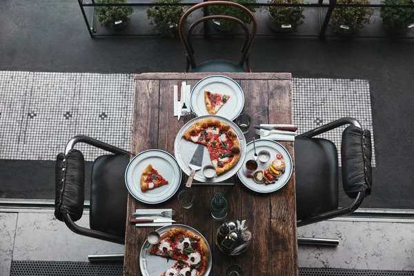 餐厅木桌上美味的比萨饼和豆腐煎饼的顶级视图 — 免费的图库照片