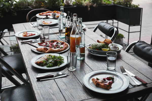 different italian dishes and drinks on wooden rustic table at restaurant