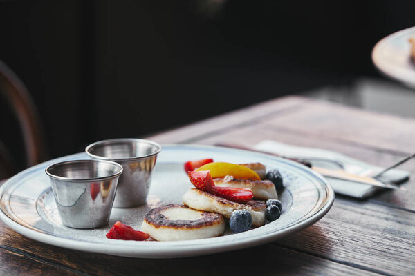 close-up shot of delicious cheese pancakes with bowls of dippings on wooden table