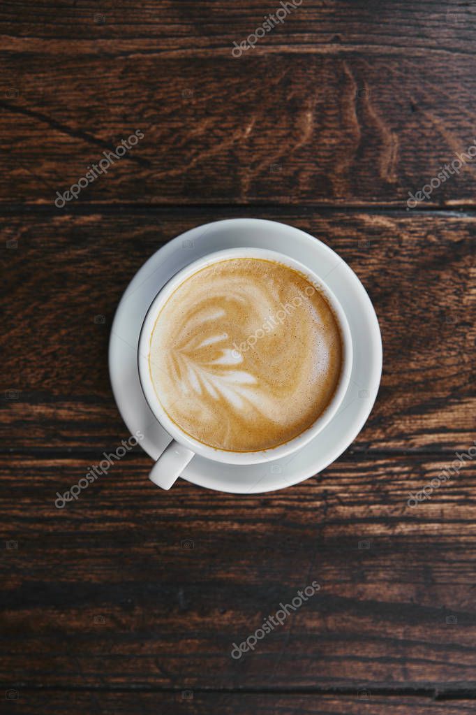 Top view of cup of delicious coffee on rustic wooden table
