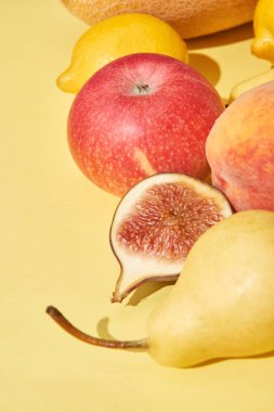 close-up view of fresh ripe pear, apple, peach, fig and lemons on yellow clipart