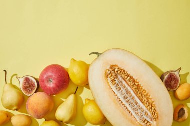 top view of halved melon and fresh ripe fruits on yellow background clipart