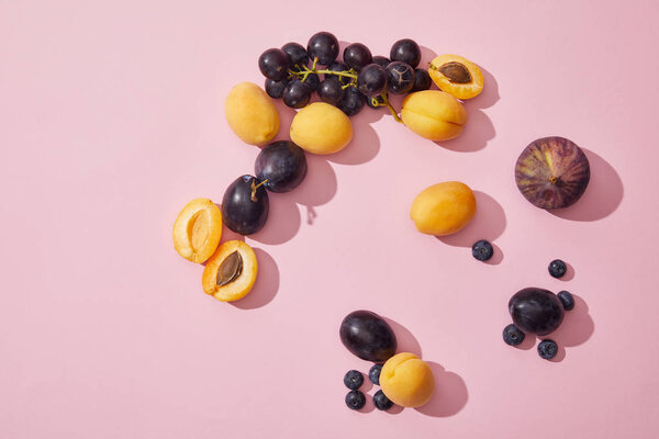 верхний вид свежих спелых сладких абрикосов, винограда, сливы, черники и инжира на фиолетовом фоне
