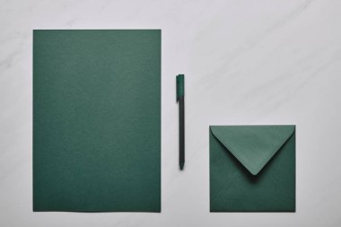 Zarf ve kalem beyaz mermer zemin üzerine yeşil mektup şablonu