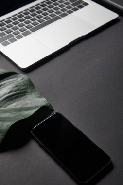 Siyah arka plan üstünde laptop tarafından boş ekran ile Smartphone