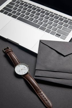 Black envelops and watch by laptop on black background clipart