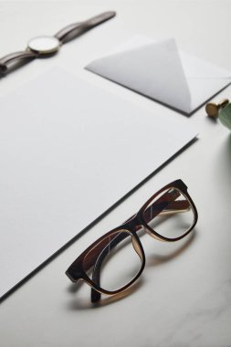 Zarf ve beyaz mermer zemin üzerine gözlük ile kompozisyon
