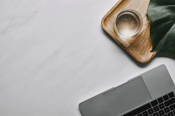 Laptop Mit Holztablett Und Wasserglas Auf Weißem Marmorhintergrund — Stockfoto