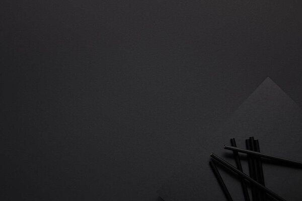 Black pencils and paper on black background