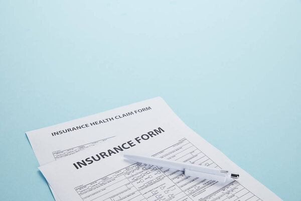 close-up view of insurance form, insurance health claim form and pen isolated on blue