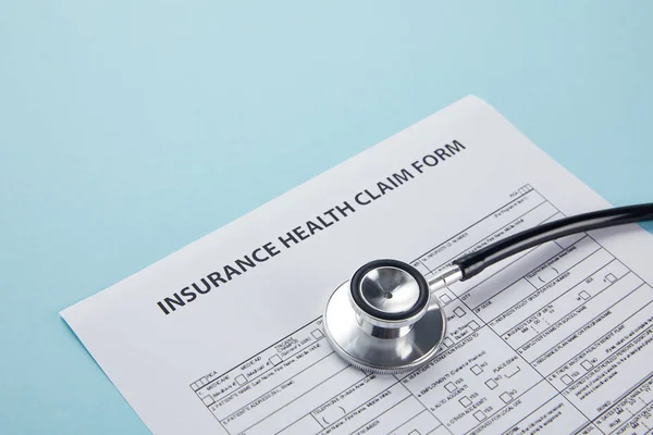 close-up view of insurance health claim form and stethoscope isolated on blue