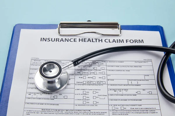 Nahaufnahme Des Versicherungsantragsformulars Auf Klemmbrett Und Stethoskop Auf Blau — Stockfoto