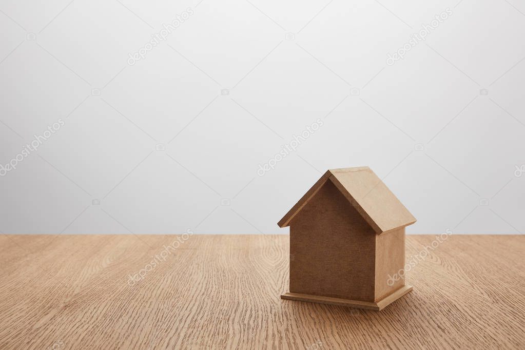 Close-up view of small house model on wooden table on grey, insurance concept