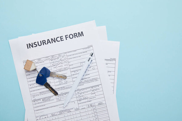 top view of insurance form, keys and pen isolated on blue 