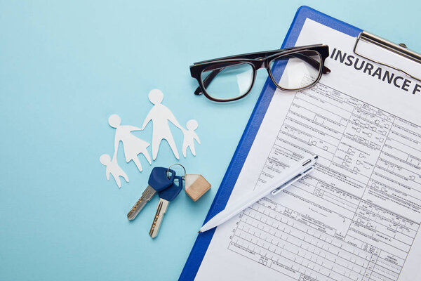 top view of insurance form, pen, paper cut family and keys isolated on blue  