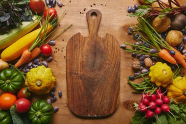 Cutting board with summer vegetables on wooden table