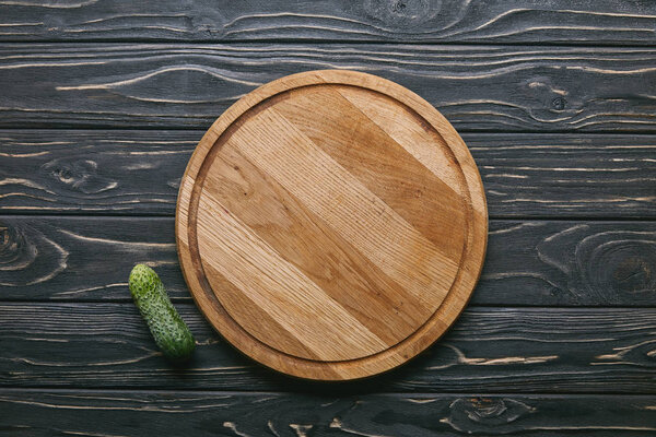 Cutting board and cucumber on dark wooden table