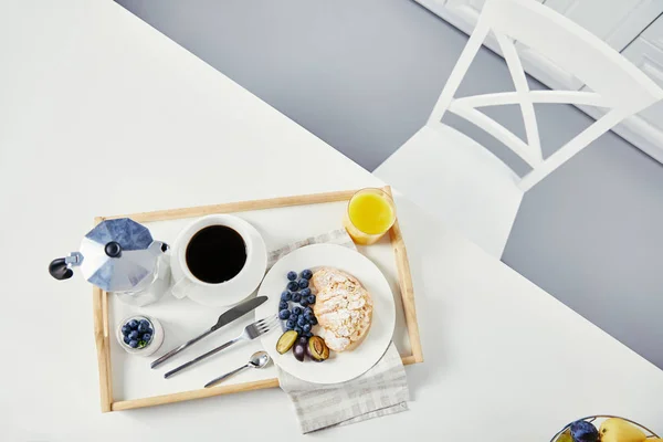 クロワッサン 新鮮なブルーベリーと梅ジュースのグラス コーヒーと白い卓上の朝食の木製トレイにヨーグルトのカップの上から見る — ストック写真