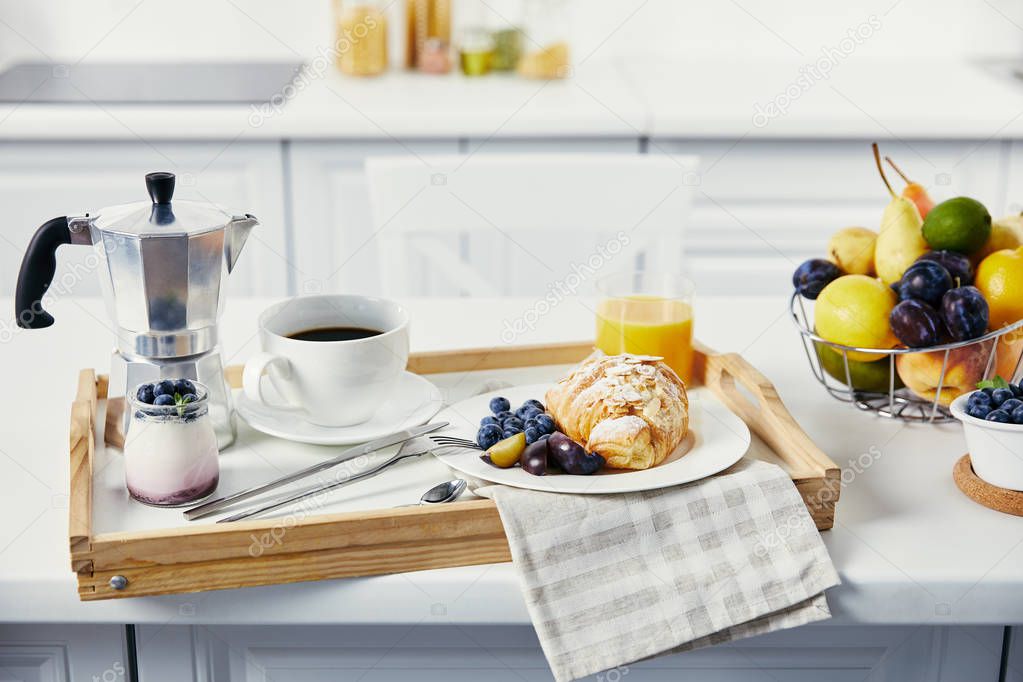close up view of tasty breakfast with cup of coffee and glass of juice on wooden tray on white surface