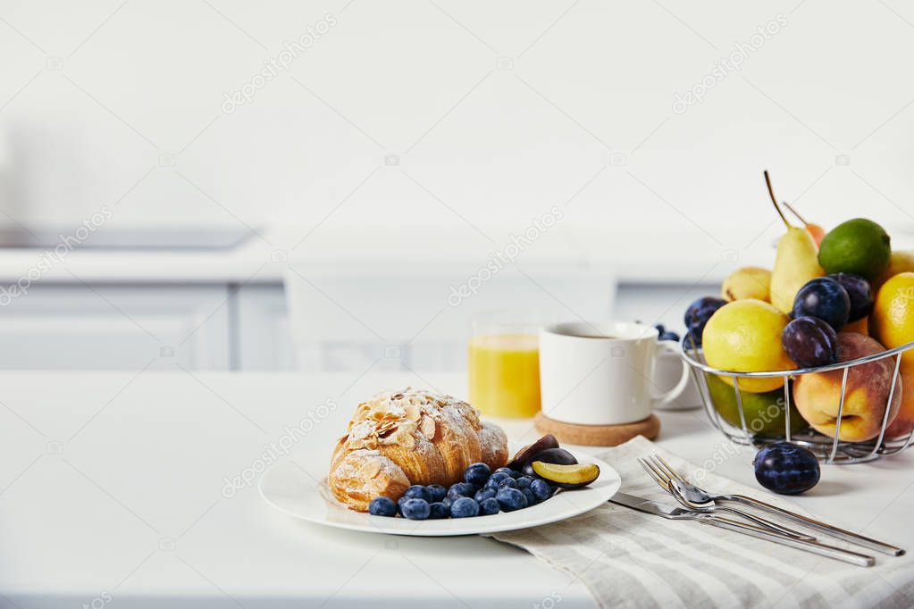 close up view of tasty breakfast with croissant and cup of coffee on white surface