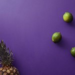 Ansicht von Ananas und Limetten auf violetter Oberfläche