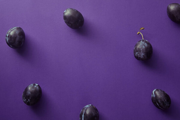 top view of ripe plums on violet surface